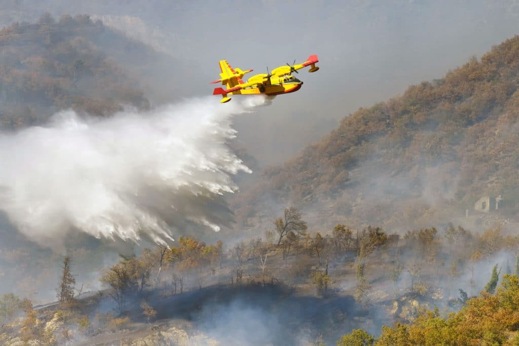 yellow aircraft water drop on forest fire